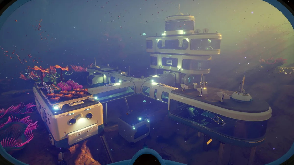 An underwater base illuminated with lights, featuring interconnected modules and vibrant coral in an ocean setting from the game Subnautica.