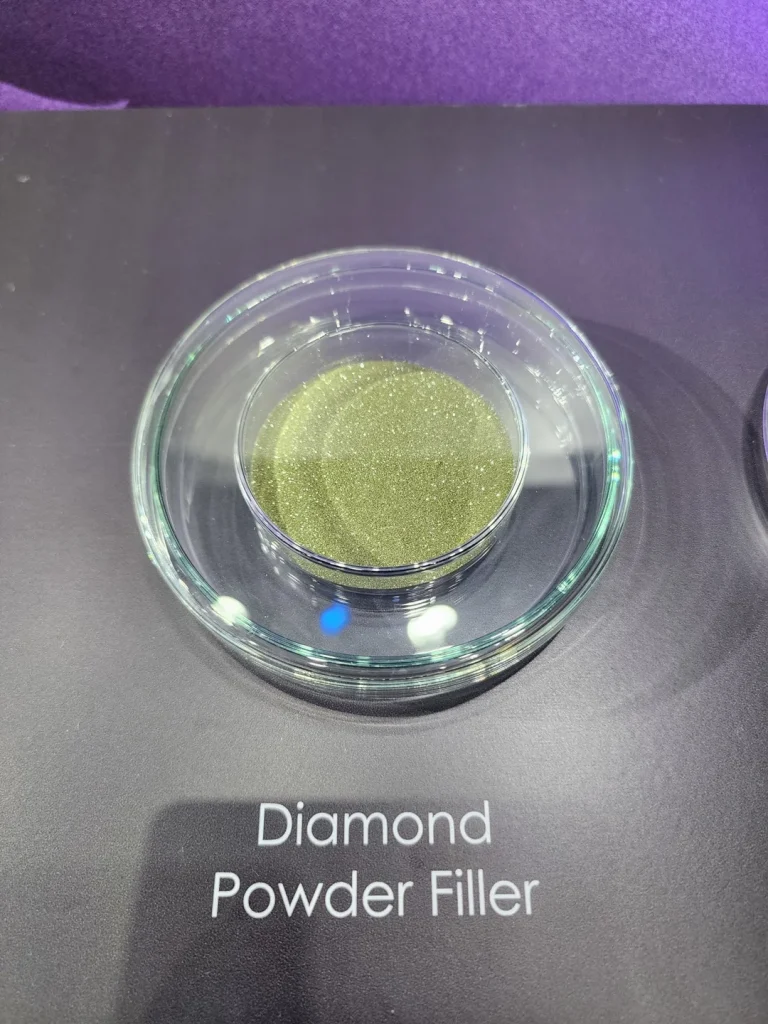 A glass dish containing green Diamond Powder Filler is displayed on a black surface.