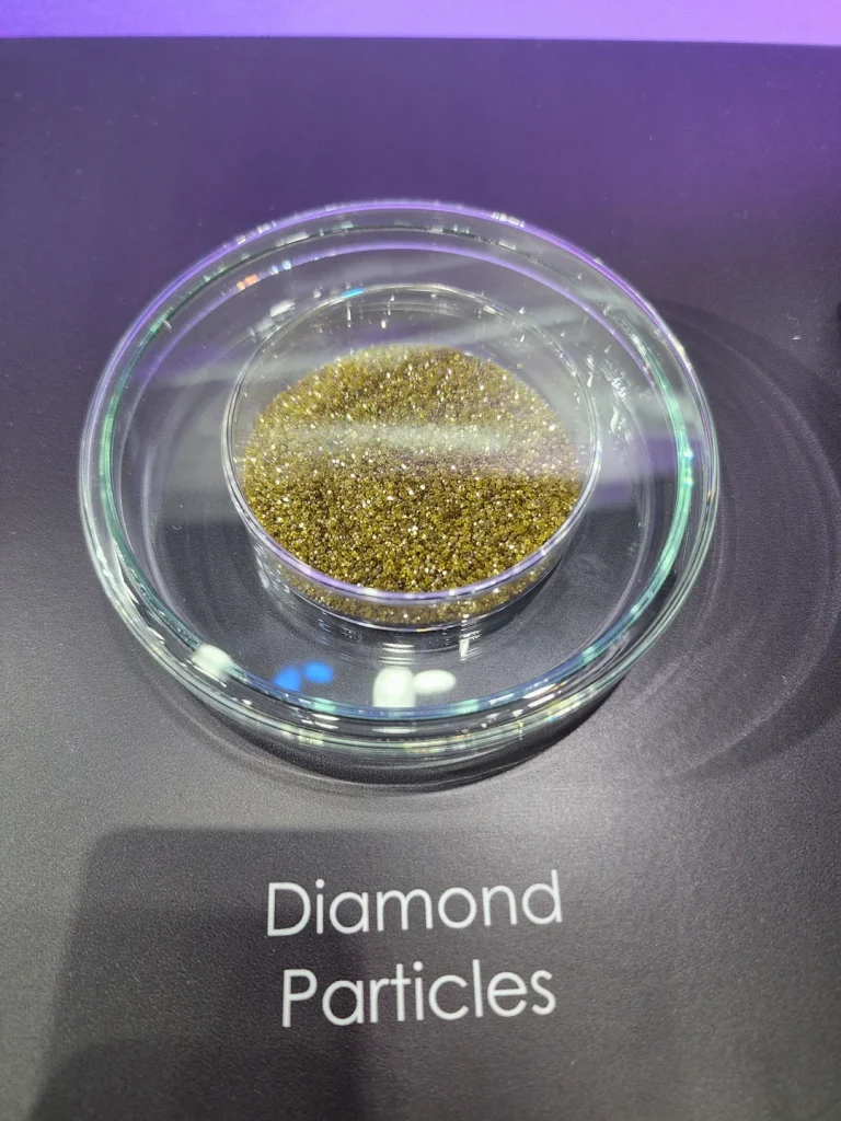 A petri dish containing diamond particles is placed on a surface labeled 'Diamond Particles.'