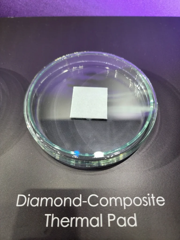 A small gray square labeled as a Diamond-Composite Thermal Pad is displayed on a glass dish with a purple background.