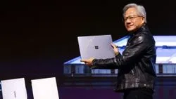 Nvidia CEO Jensen Huang holding a laptop on stage at Computex 2026