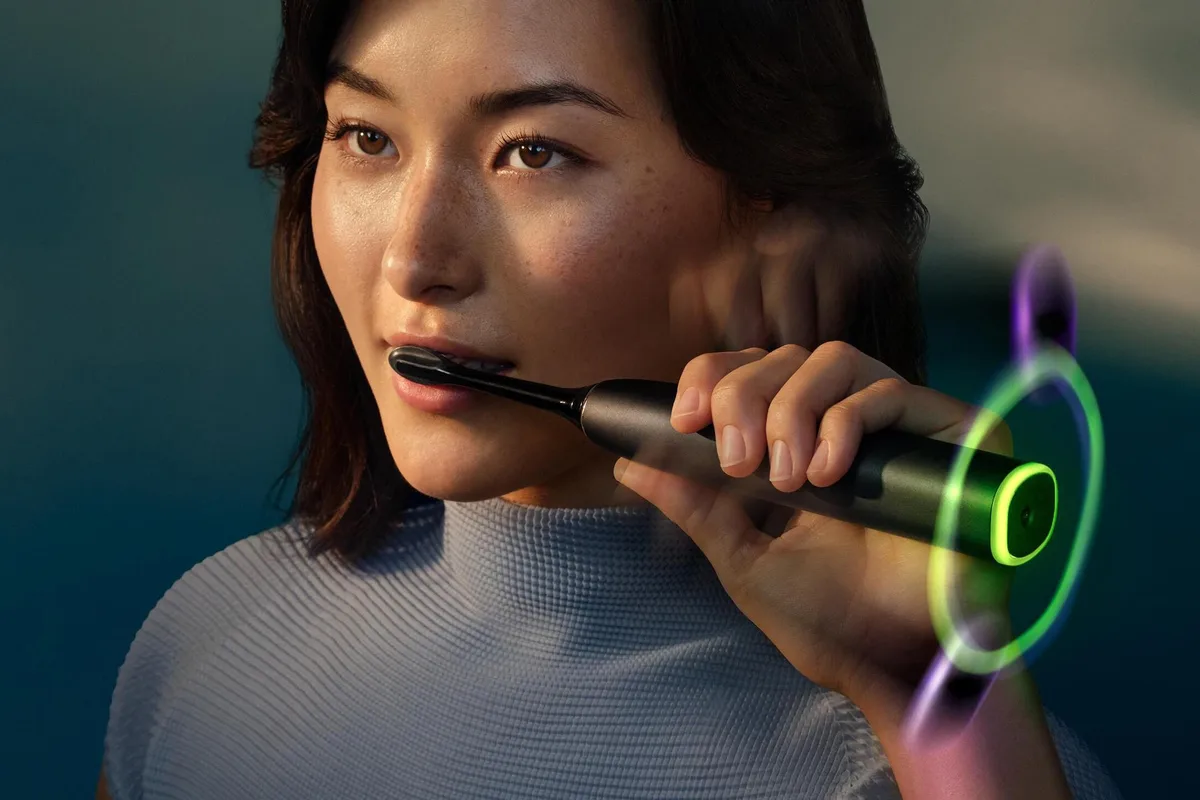 Philips Sonicare DiamondClean 9900 — A person brushes with the Philips Sonicare Next-Generation DiamondClean 9900 Prestige smart toothbrush while a glowing ring around its base changes colors.