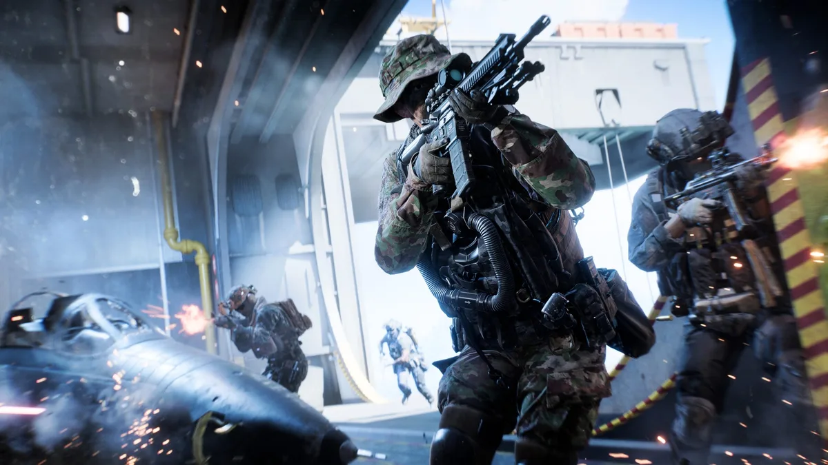 Soldiers in camouflage gear carrying rifles advance through a military hangar in a dynamic action scene from a first-person shooter video game.