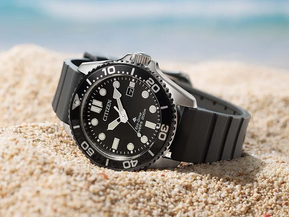 citizen promaster diver precio — Citizen Promaster Marine BN0266-07E with a black dial, black bezel, and black strap resting on sand.