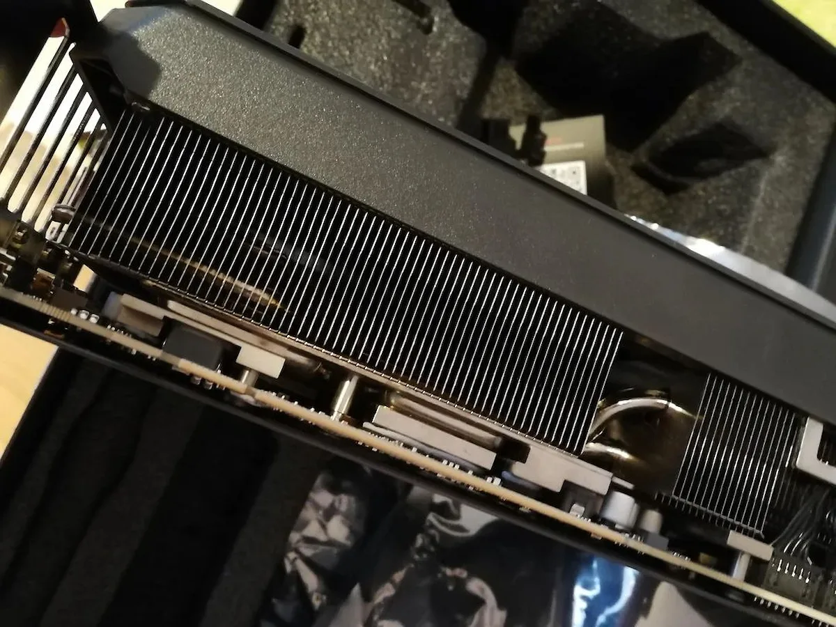 GIGABYTE devolución GPU rechazada — A close-up view of an unbranded graphics card with exposed cooling fins and heat pipes in a foam-lined box.