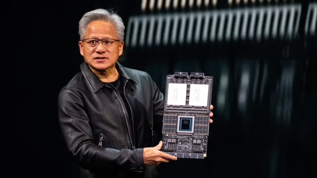 nvidia oberon nvl72 — A presenter in a black leather jacket holds a large computing board with visible components and circuitry.