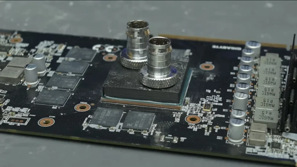A Gigabyte graphics card is displayed with exposed Samsung memory chips and a custom liquid cooling block installed on the GPU.