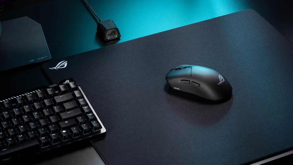 The black ROG Gladius IV Ace on a black desktmat beside an ROG keyboard.