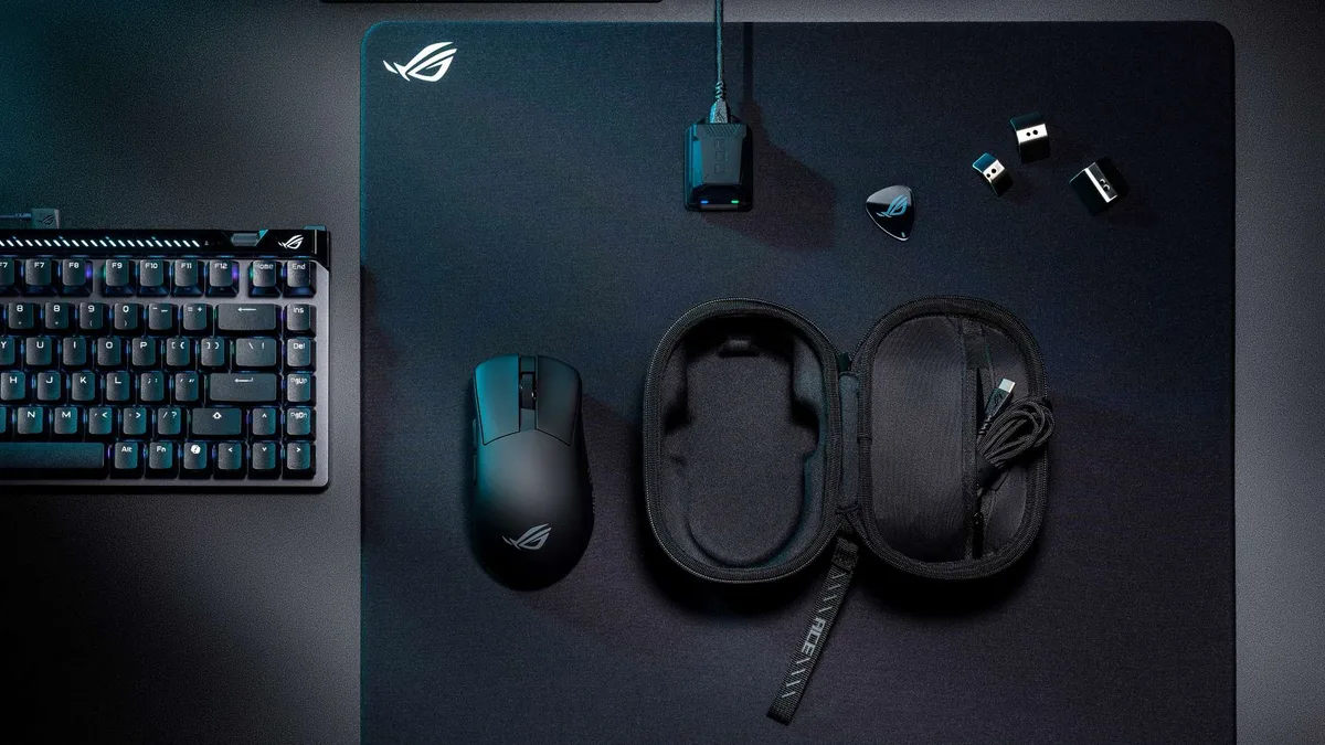 The Rog Gladius IV Ace Gaming — The ROG Gladius IV Ace on a black desktmat atop a grey table surrounded by accessories.