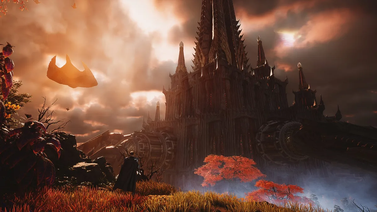 A character in a dark cloak stands before a large, gothic fortress under a dramatic sunset sky, with vibrant red foliage and floating rocks in the scene from a fantasy game.