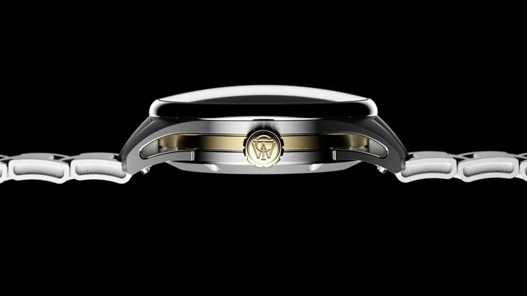 Side profile of the Timex Atelier GMT Première M1a highlighting its curved sapphire crystal, stainless steel case, and gold-tone center section.