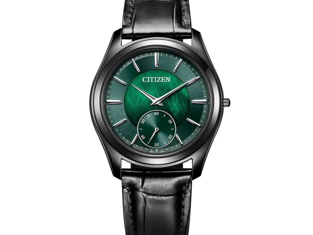 Angled close-up of the Citizen Eco-Drive One AQ5025-04N showing its shimmering green mother-of-pearl dial, silver-tone hands and markers, black case, and leather strap.