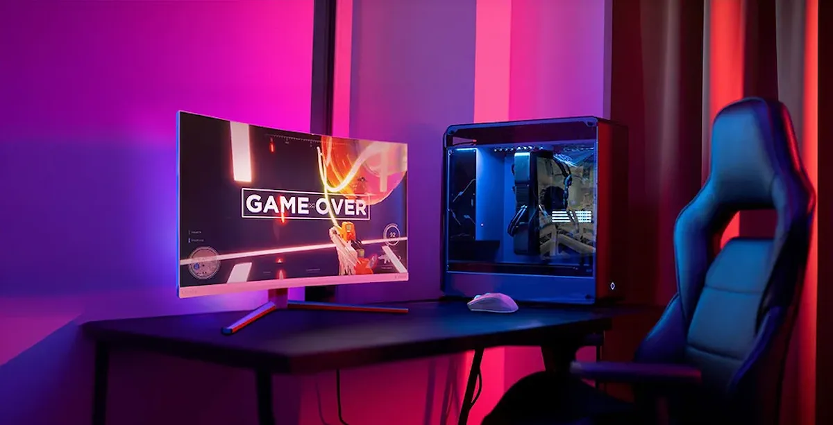 Configuración de escritorio gaming con monitor Philips Evnia curvo, torre de PC con iluminación interna y silla ergonómica en una habitación con luz ambiental púrpura.