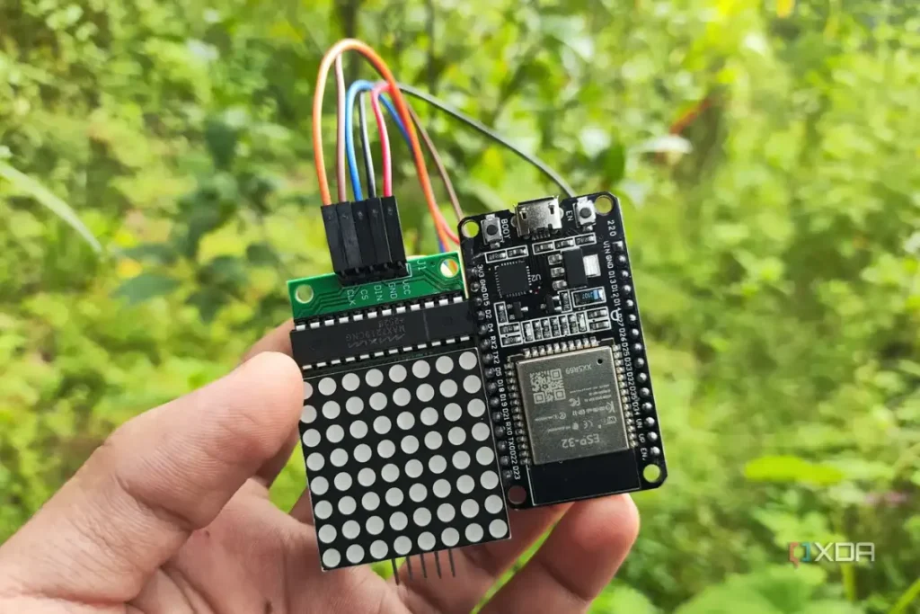 que esp32 elegir — A person holding an ESP32 connected to a matrix display