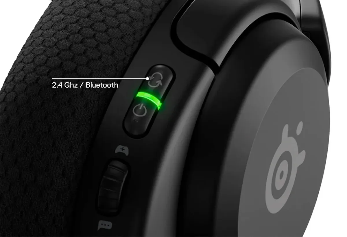 Detalle de los botones de control de unos auriculares SteelSeries Arctis Nova 5x con el indicador LED encendido en verde.