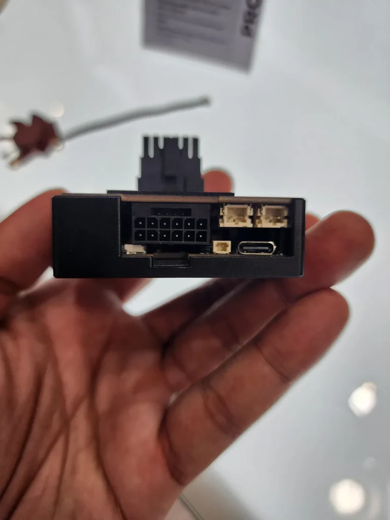 A hand holding a PCIe adapter with visible connectors including an 8-pin, two 4-pin, and a USB Type-C port.