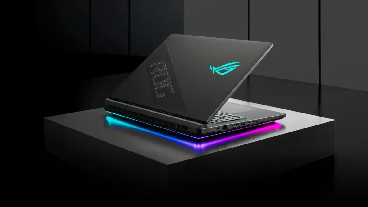 Portátil gaming ASUS ROG entreabierto sobre una plataforma, con logotipo iluminado en la tapa e iluminación RGB en la base