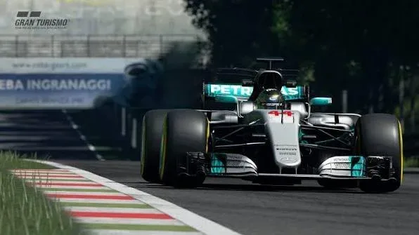 Monoplaza plateado de Mercedes de Fórmula 1 con publicidad de Petronas avanza hacia la cámara junto a un piano rojiblanco en Gran Turismo Sport