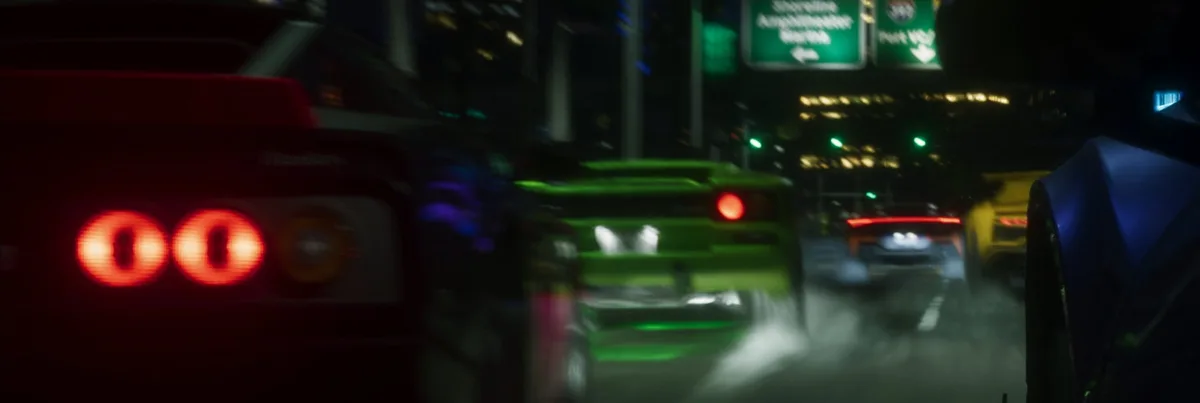 Grupo de coches deportivos, entre ellos uno verde, circula de noche por una calle de la ciudad
