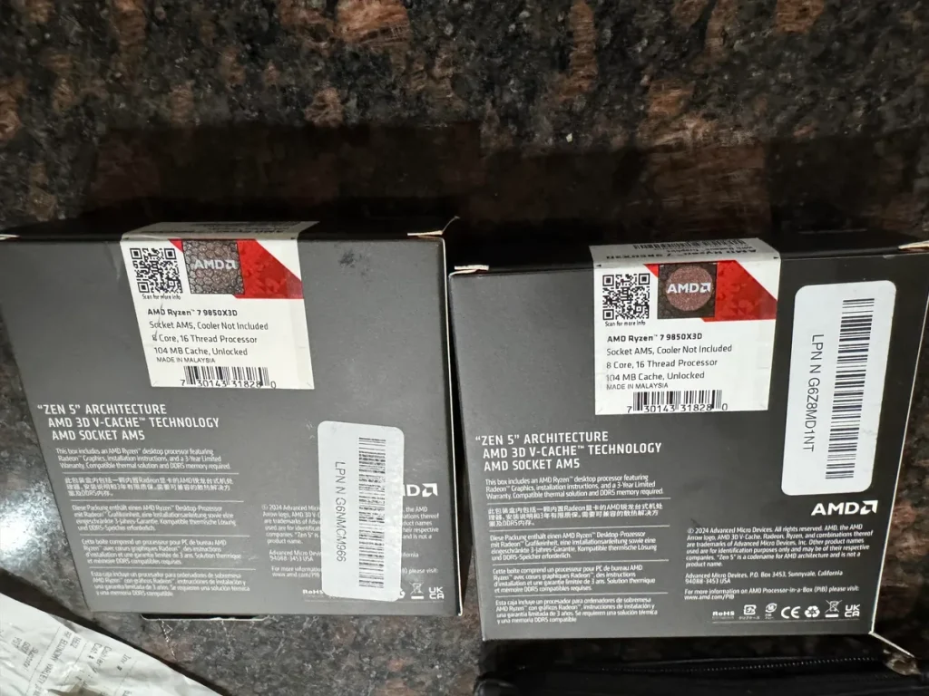 Two boxes of AMD Ryzen 7 5800X3D processors featuring 'Zen 5' architecture and 'AMD 3D V-Cache' technology are shown on a stone surface.