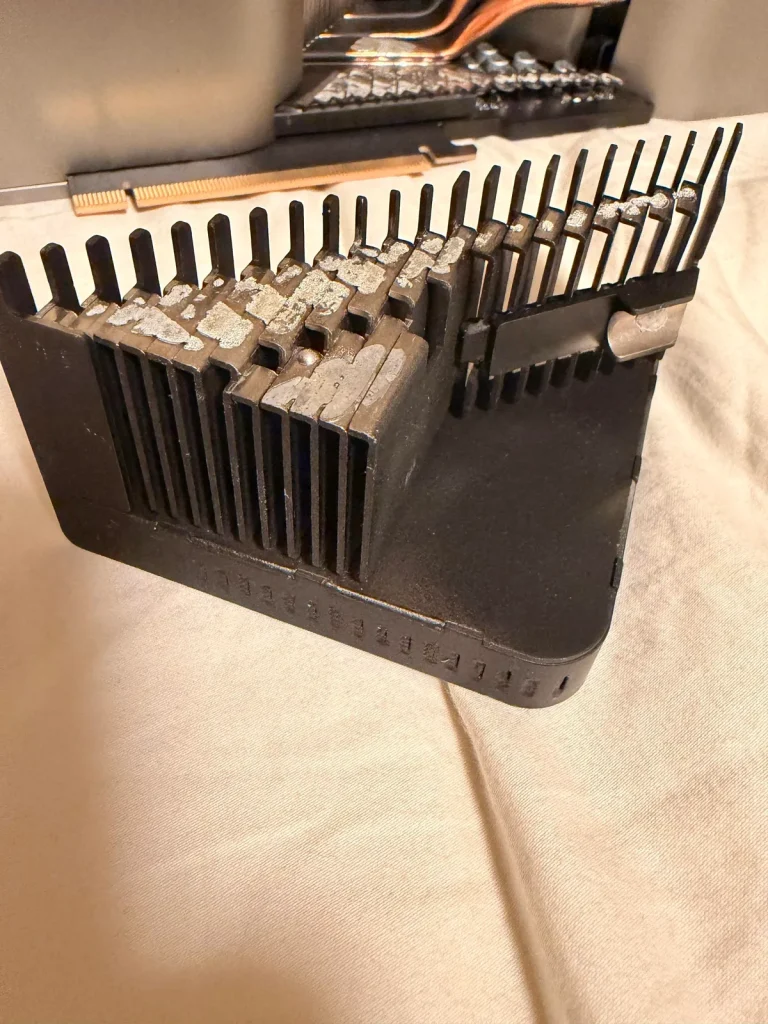 A detailed close-up of a large, unbranded heat sink with cooling fins, placed on a beige surface, with thermal paste residue visible on the contact area.