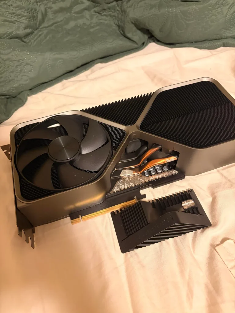RTX 4090 Founders Edition — A disassembled NVIDIA graphics card with a large cooling fan and visible heat pipes on a bed.