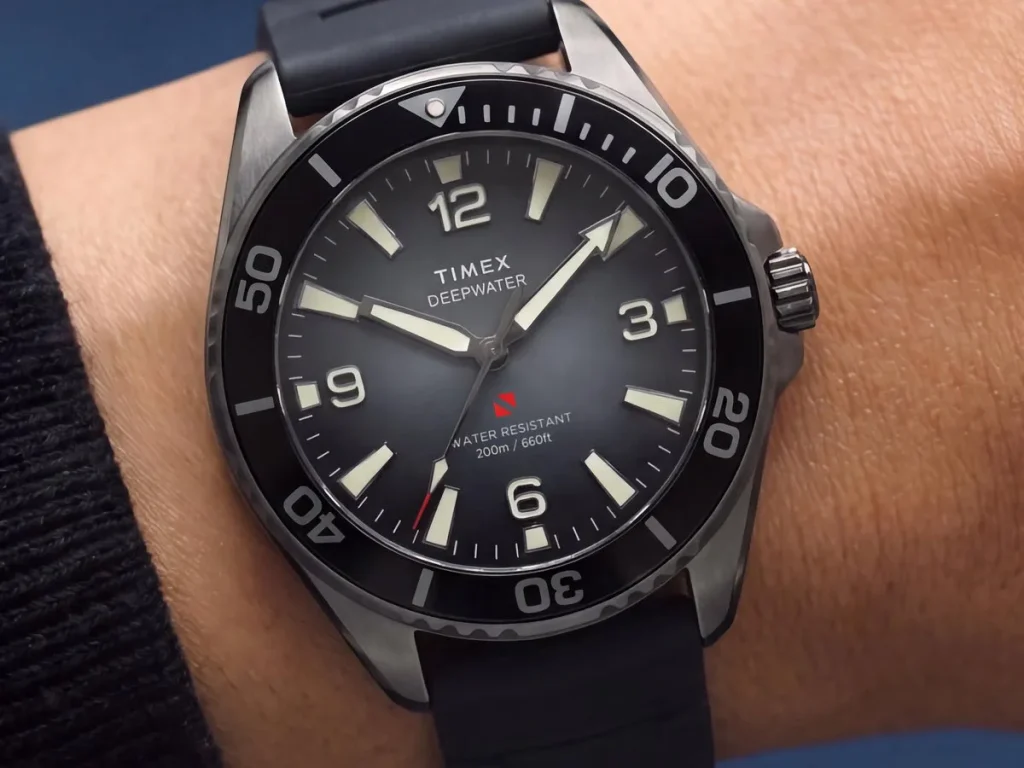 Timex Deepwater Arctic 200 dive watch with a smoky dégradé dial, black ceramic bezel, luminous hour markers, and black rubber strap, shown on a wrist.